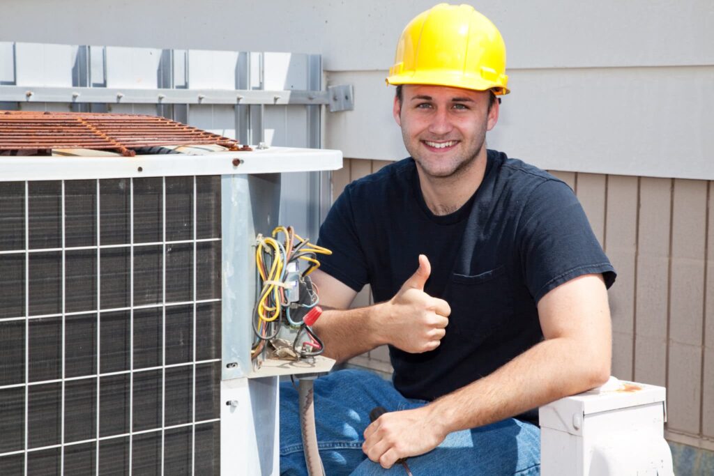 HVAC technician giving thumbs up near air conditioner.
